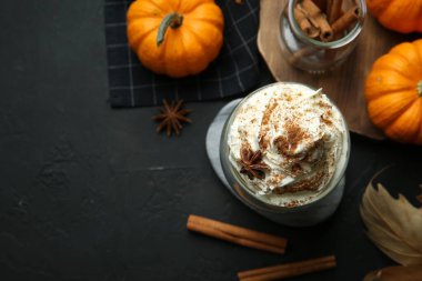 Siyah masanın üzerinde bir bardak balkabağı aromalı latte ile düz bir kompozisyon vardı. Metin için boşluk