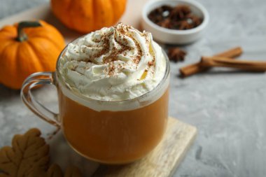 Açık gri masada kremalı balkabağı aromalı latte, yakın plan.