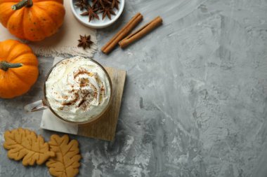 Krem şantili balkabağı aromalı latte. Kurabiye ve malzemeler açık gri masada. Metin için boşluk