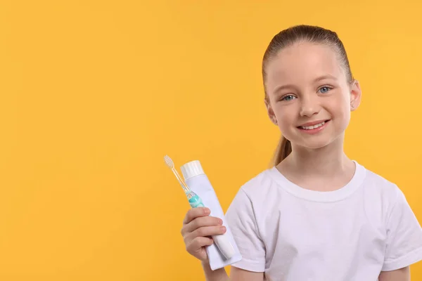 Szczęśliwa Dziewczyna Trzyma Elektryczną Szczoteczkę Zębów Tubkę Pasty Żółtym Tle — Zdjęcie stockowe