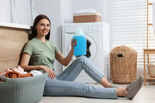 Frau Sitzt Auf Fußboden Neben Waschmaschine Und Hält Weichspüler Badezimmer — Stockfoto