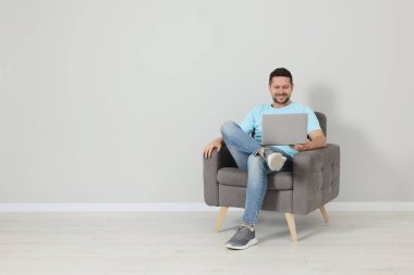 Mutlu adam koltukta oturuyor ve bilgisayarını içeride kullanıyor, mesaj için yer var.