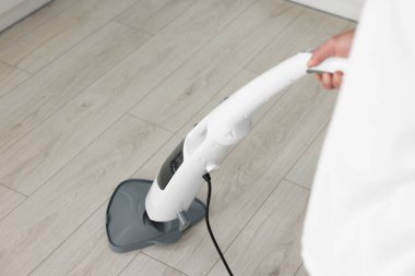 Evin zeminini buharlı paspasla temizleyen adam, yakın çekim.