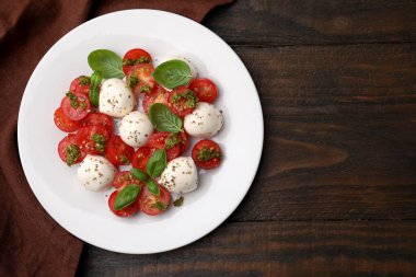 Domatesli Caprese salatası, mozzarella topları ve ahşap masada fesleğen. Metin için boşluk