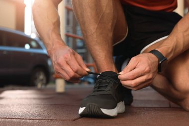 Spor salonunda antrenmandan önce ayakkabı bağcıklarını bağlayan adam, yakın plan.
