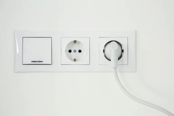 室内白色墙上插插头和电灯开关的电源插座 — 图库照片