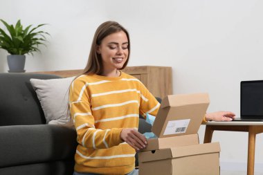 Evde paketleri açan mutlu kadın. Çevrimiçi mağaza