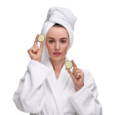 Bornozlu, beyaz arka planda salatalık parçaları olan güzel bir kadın.