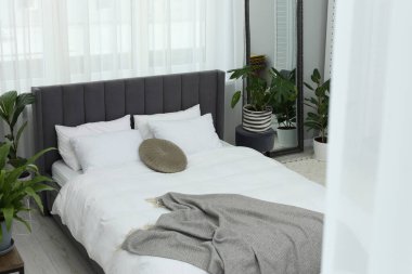 Büyük, rahat bir yatak ve güzel bitkiler. Yatak odasının içi.