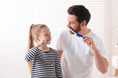 Babası ve kızı içeride dişlerini fırçalıyorlar.