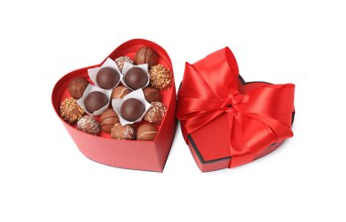 Kalp şeklinde bir kutu, beyaz üzerine izole edilmiş lezzetli çikolata şekerlemeleri.