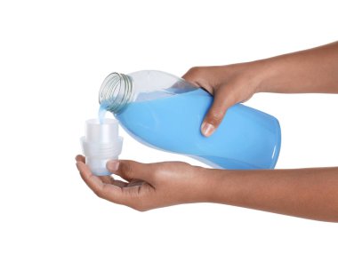 Kadın beyaz arka planda şişeden kapağa yumuşatıcı döküyor, yakın plan.