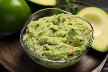 Maydanozlu lezzetli guacamole ve ahşap tahtada taze avokado, yakın plan.