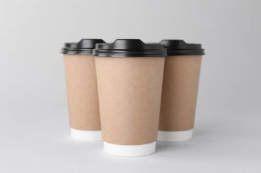 Açık gri arka planda siyah kapaklı kağıt bardaklar. Kahve hazır.