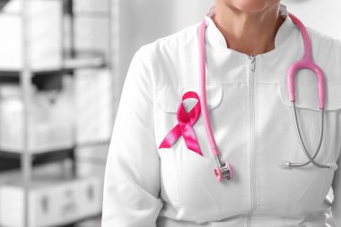 Steteskop ve pembe kurdeleli bir doktor. Kapalı mekanda ve mesaj için yer var. Göğüs kanseri farkındalığı