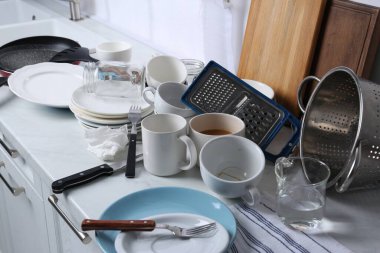 Many dirty utensils and dishware on countertop in messy kitchen clipart