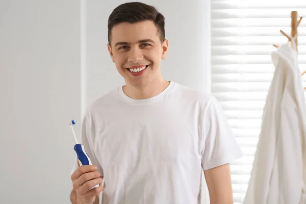 バスルームに電気歯ブラシが付いている幸せな男 — ストック写真