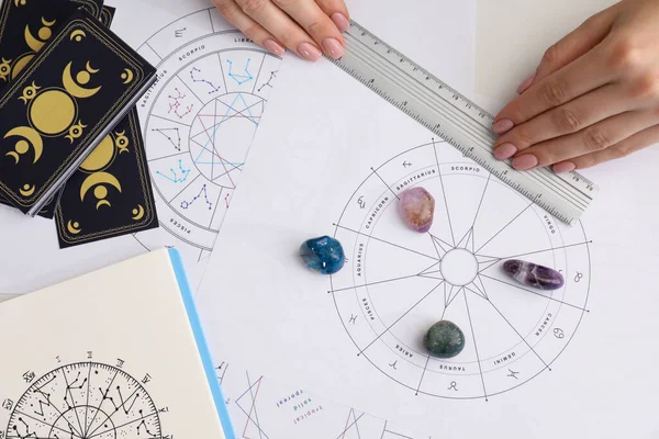 Astrologer using zodiac wheel for fate forecast at table, top view. Fortune telling