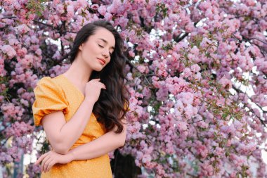 Bahar günü çiçek açan sakura ağacının yanında güzel bir kadın.