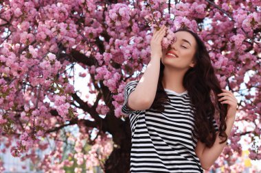 Bahar günü çiçek açan sakura ağacının yanında güzel bir kadın.