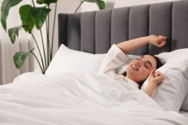 Evde yatakta uyanan mutlu bir kadın, mesaj için yer. Tembel sabah