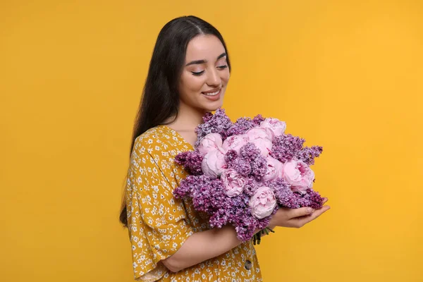 黄色の背景に春の花の花束が付いている美しい女性 — ストック写真