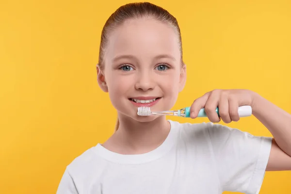 Щаслива Дівчина Чистить Зуби Електричною Зубною Щіткою Жовтому Фоні — стокове фото