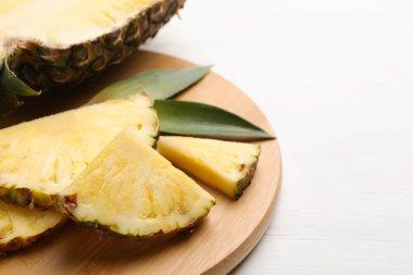 Beyaz ahşap masada olgun sulu ananas dilimleri, yakın plan. Metin için boşluk