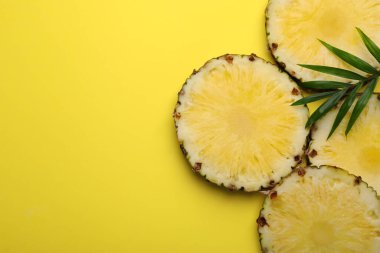 Sarı arka planda lezzetli olgun ananas ve yeşil yapraklar var. Metin için boşluk