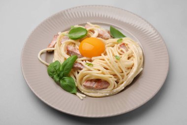 Açık mavi arka planda yumurta sarısı olan lezzetli Carbonara makarnası, yakın plan.