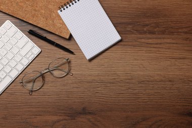 Farklı kırtasiye malzemeleri, bilgisayar klavyesi ve tahta masadaki gözlükler, mesaj için yeri olan düz bir yer. Merkez Ofis