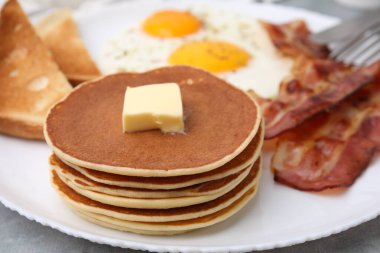 Gri masada omlet ve pastırmayla servis edilen leziz krepler, yakın plan.