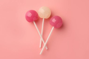 Pembe arka planda leziz lolipoplar, düz yatış