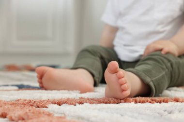 Bebek içeride yumuşak halıda oturuyor, yakın plan. Metin için boşluk
