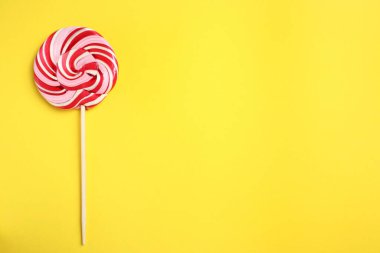 Sarı arka planda renkli lolipop kıvrımlı, üst manzaralı. Metin için boşluk