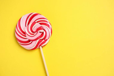 Sarı arka planda renkli lolipop kıvrımlı, üst manzaralı. Metin için boşluk