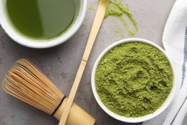 Yeşil kibrit tozu ve açık gri masada taze içecek içeren düz bir kompozisyon.