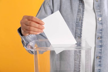 Oy sandığına oy veren kadın turuncu arka planda, yakın plan.