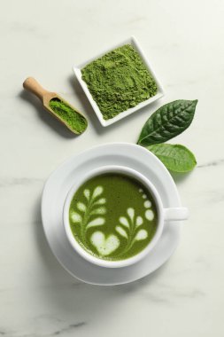 Delicious matcha latte, powder and leaves on white marble table, flat lay clipart