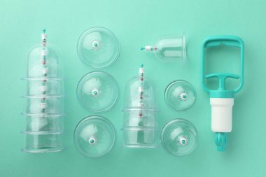 Turkuaz arka planda plastik bardaklar ve el pompamız var. Fincan terapisi.