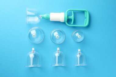 Plastik bardaklar ve el pompası açık mavi arka planda, düz yerde. Fincan terapisi.