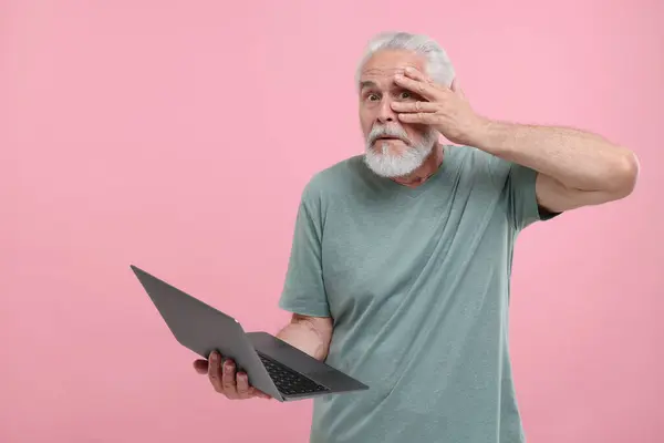 Смущенный Старший Мужчина Держит Ноутбук Розовом Фоне Пространство Текста — стоковое фото
