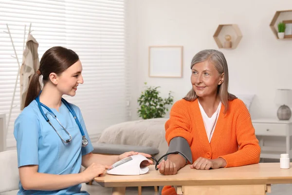 Young Healthcare Worker Measuring Senior Woman Blood Pressure Wooden Table — Stock Photo, Image