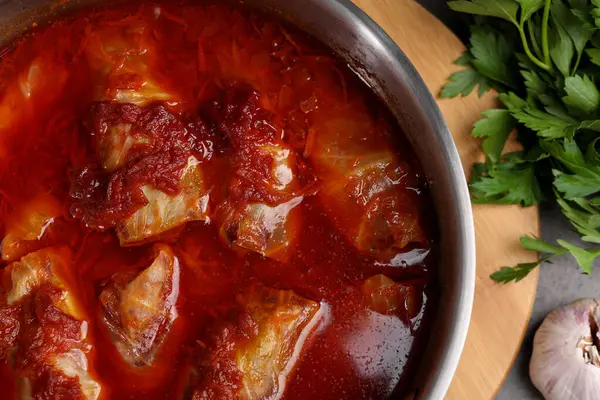 Delicious stuffed cabbage rolls cooked with homemade tomato sauce in pot on table, top view