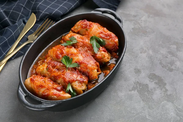 Delicious stuffed cabbage rolls cooked with tomato sauce on grey table, closeup. Space for text