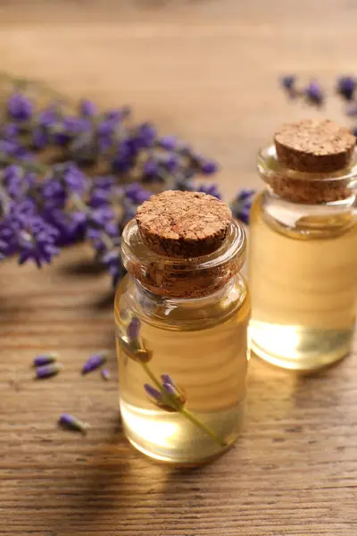 Essential oil and lavender flowers on wooden table, closeup