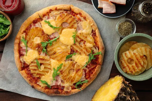 Delicious pineapple pizza and ingredients on table, flat lay