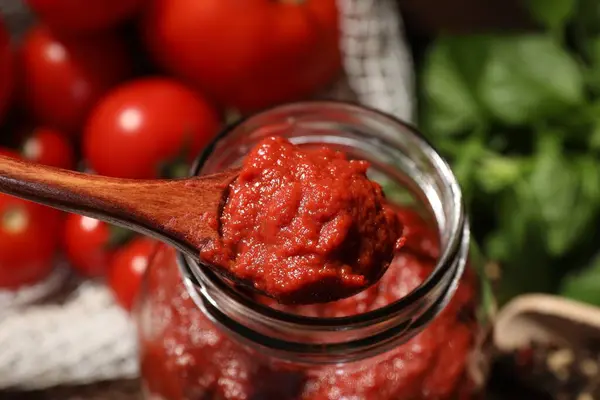 用木勺从桌上的罐子里取出好吃的番茄酱 特写镜头 — 图库照片