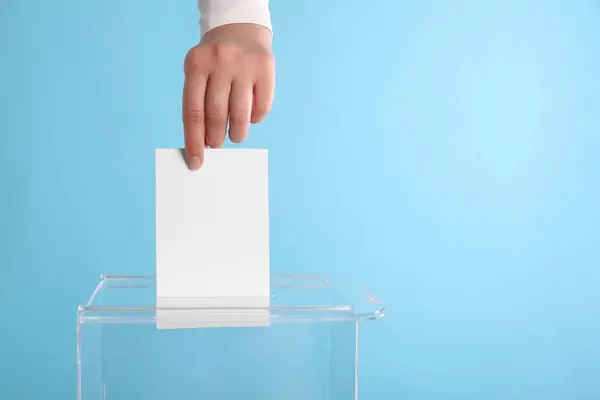 女人把她的选票放在投票箱浅蓝色背景 案文的篇幅 — 图库照片