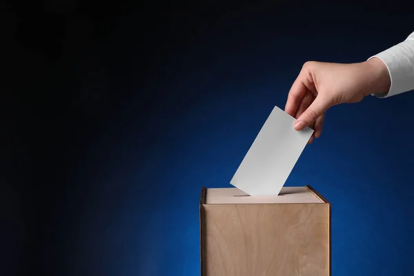 女人把她的选票放在投票箱深蓝色背景 案文的篇幅 — 图库照片